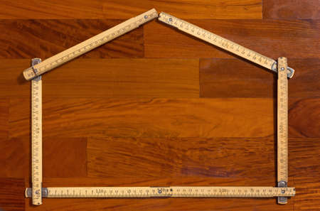Measuring stick folded in the shape of a house on a wooden backgroundの写真素材