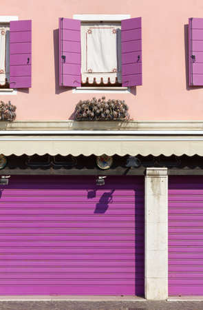 Detail of a decorated pink colored building's exterior with purple window shuttersの写真素材
