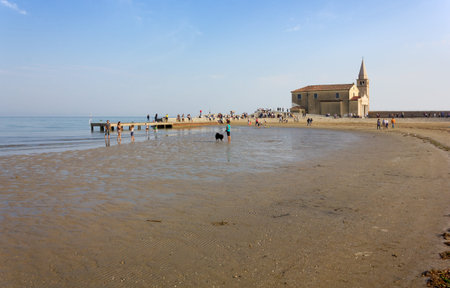 CAORLE, October 14, 2018: The beach and the pier next to the Shrine of Our Lady of the Angel crowded with people in a beautiful autumn afternoonのeditorial素材