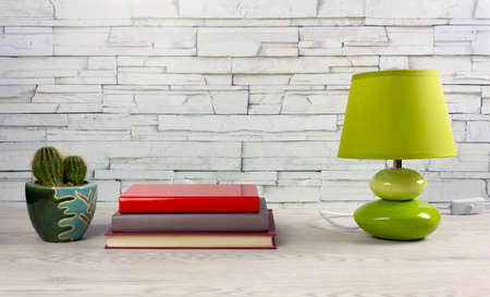 White wooden desk with a few books, a modern table lamp and a small cactusの写真素材
