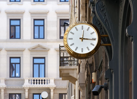 Closeup of a golden colored clock on an elegant urban street