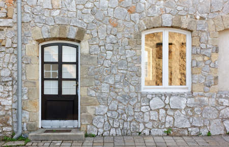 Facade of a historic building with a wooden door and a windowの写真素材