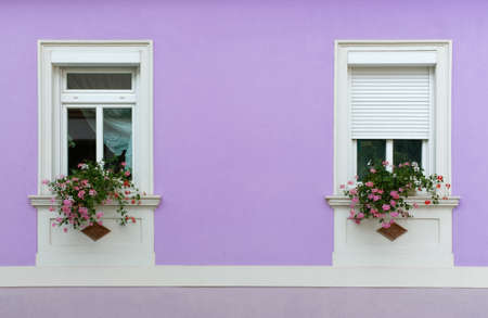 Close-up of the facade of an elegant house, with geranium flowerpots on the windowsillsの写真素材