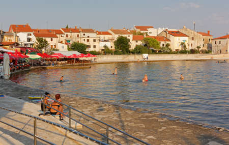 UMAG, Croatia - August 12, 2015: Tourists and bathers crouding the seafront of the old town during a summer sunsetのeditorial素材