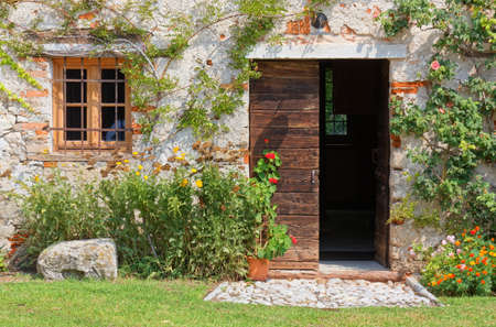 Exterior of an old traditional rural building decorated with plants and flowersの写真素材