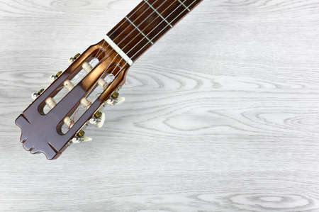 Head and neck of a classical guitar on a white wooden table, with copy spaceの写真素材