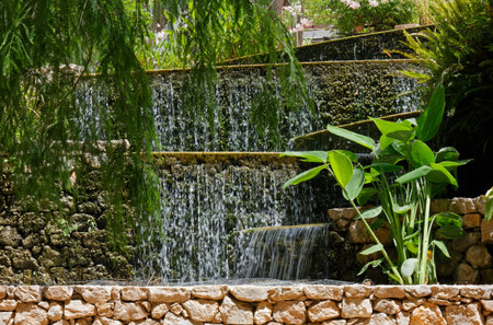 Artificial waterfall in a park among plants and tree branches
