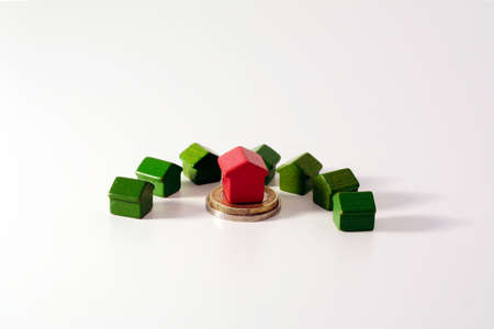 Financial crisis and housing market symbolized by euro coins and tiny wooden houses red and greenの写真素材