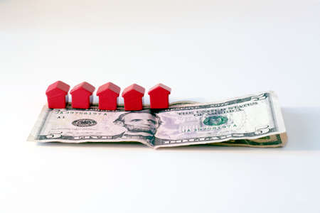 Financial crisis and housing market symbolized by dollar bills and tiny red wooden housesの写真素材