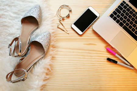Top view wooden table desk for a fashion blogger on social media. Workspace with white fluffy rag, laptop and feminine accessories. Lay flat.のeditorial素材