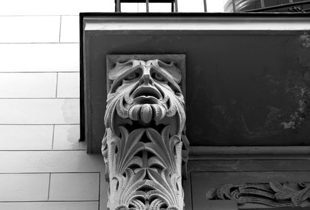 The sculpture of a face on the facade of the building. Black and white.