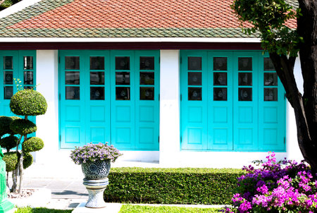 Thai style house with blue door and flower pot in garden.