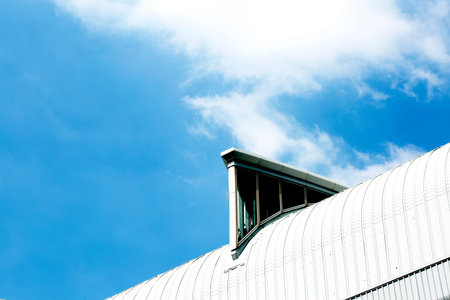 Roof of a modern building against a blue sky with white clouds