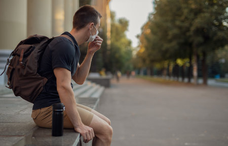 Man in a protective mask sits on parapet