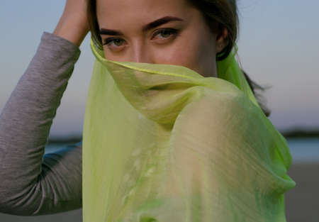 Green eyes of a girl looking at the camera with a covered faceの写真素材