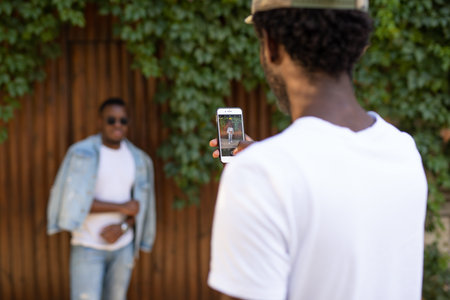 African man shooting friend in white t-shirt on the smartphone