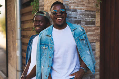 Happy african man in jeans jacket on the background brick wallの写真素材