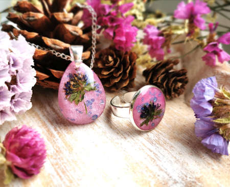 silver handmade jewelry with natural flowers, pink epoxy resin, drop shaped pendant and round ringの写真素材