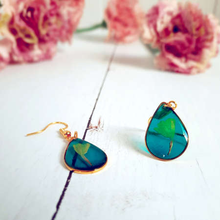 golden earrings with painted yellow flower, blue and transparent epoxy resin, teardrop shape jewelry, handmadeの写真素材