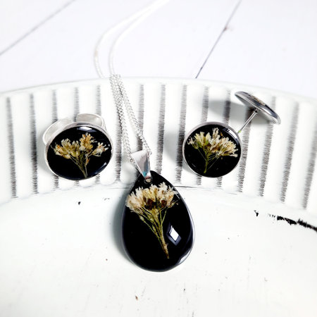 white dried flower embedded in black epoxy resin, golden chain necklace, earrings, setの写真素材