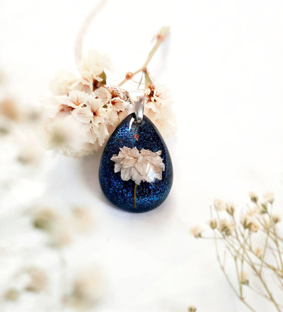drop-shaped necklace with a natural white flower inside, navy blue color, epoxy resinの写真素材