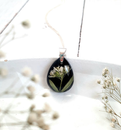 white dried flower embedded in black epoxy resin, golden chain necklaceの写真素材