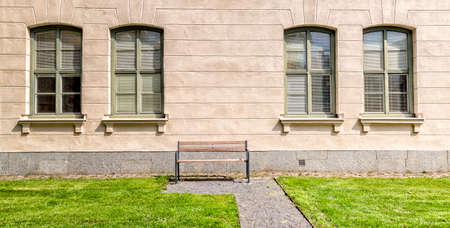Bench in front of Windows on building with grass.の写真素材