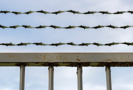 Rusty Gate with Barbed Wire with sky behind it.
