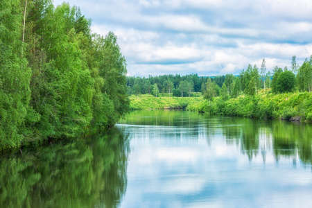 Umea River in Northern Sweden with a lot of trees and a cloudy sky.の写真素材
