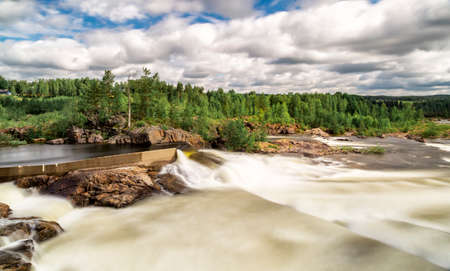 Stornorrfors, Umea River in Sweden with forest and a cloudy sky.の写真素材
