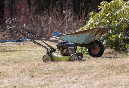 Wheelbarrow and Lawnmower in Garden.の写真素材