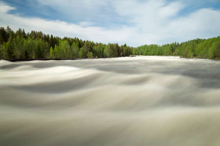 The rapids at Renforsen in Vindeln, Sweden with a partly cloudy sky.の写真素材