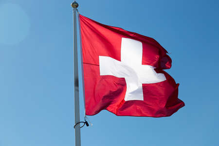 The Flag of Switzerland with a blue sky.の写真素材