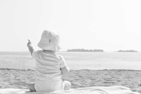 Baby Pointing to the Sky by Ocean in black and white.の写真素材