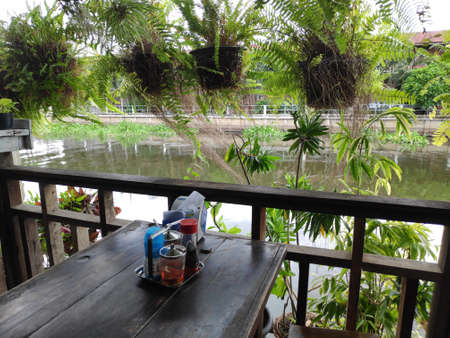 The dining table beside the canal, decorated with ornamental plants in pots, makes the atmosphere shady and beautiful.の写真素材