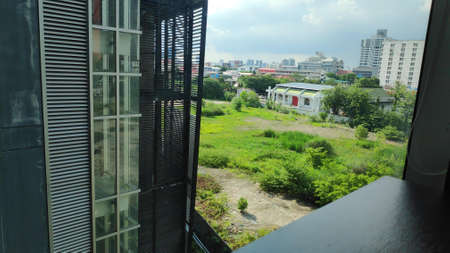 View of sky, grass, building, looking through glass window.の写真素材