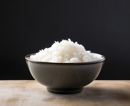 Hot steam rice in a bowl on a wooden table with black background.Rice is the staple food of Asia.の素材