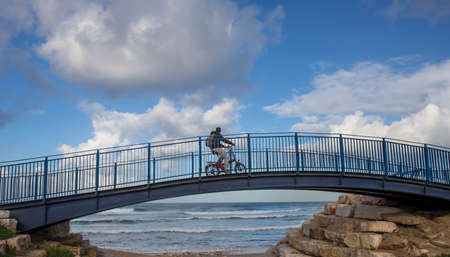 A bicycle rider on a bridge, looking at the oceanの写真素材