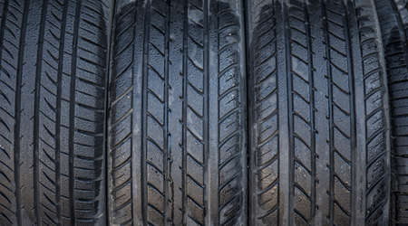 A row of car tires, wet with dew, on displayの写真素材