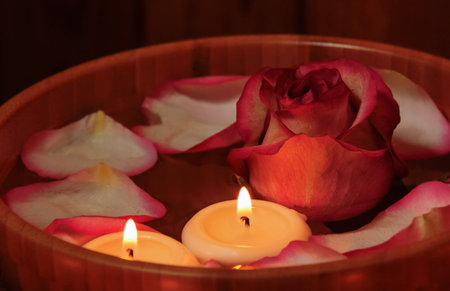 Rose petals, candles  and rose in bowl with water. Selective focus on the candleの写真素材