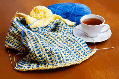 Cup of tea and knitting on wooden backgroundの写真素材