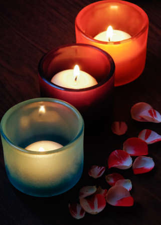 Glass candlesticks and rose petals on wooden tableの写真素材