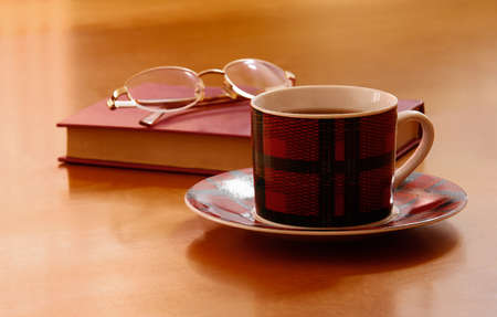 Closed  red book, glasses and tea on a wooden backgroundの写真素材