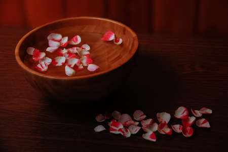 Rose petals in bowl with water on wooden tableの写真素材