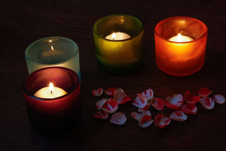 Glass candlesticks and rose petals on wooden tableの写真素材