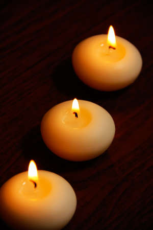 Three candles on a dark wooden table. Selective focus on the candle in the center.の写真素材