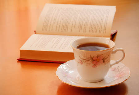 Cup of tea and opened book on wooden tableの写真素材