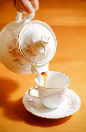 pouring tea to a teacup on wooden backgroundの写真素材