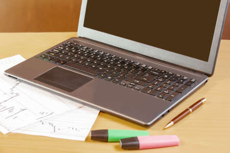 Laptop, pen and highlighters on office deskの写真素材