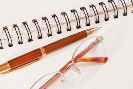 Pen, notebook and glasses on office deskの写真素材